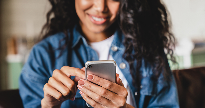 Woman Smiling While Scrolling on Phone