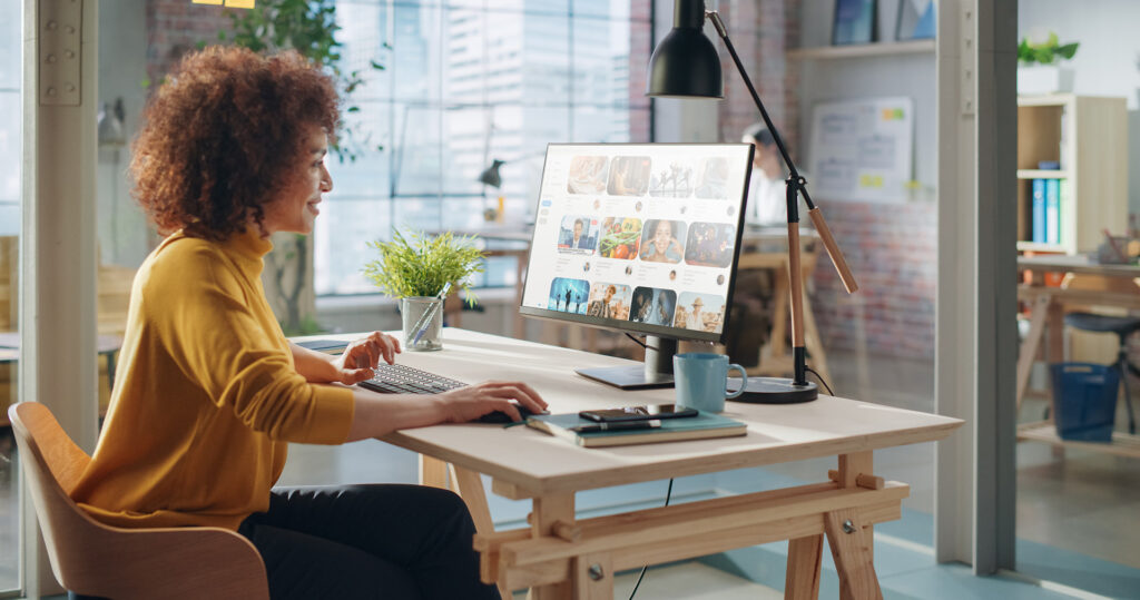 Happy Woman at Desk Looking Through Social Media Sites