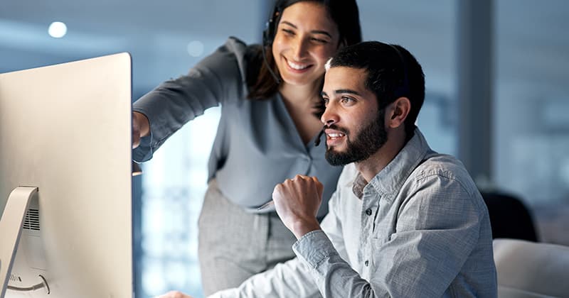 Male and female business partners looking at computer and researching
