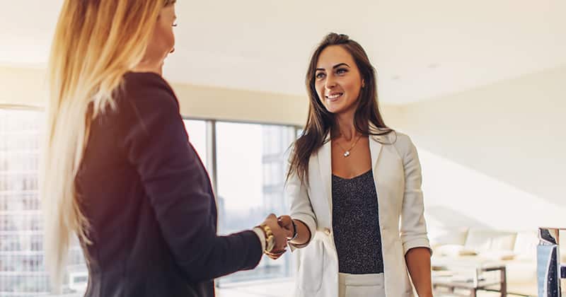 Two business women shaking hands after closing deal