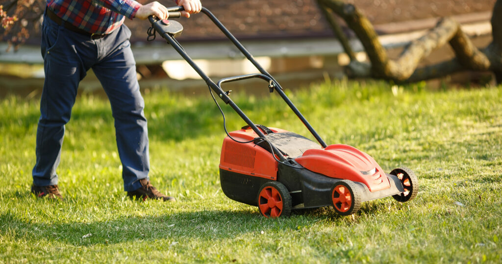 Man pushing a mower across a lawn