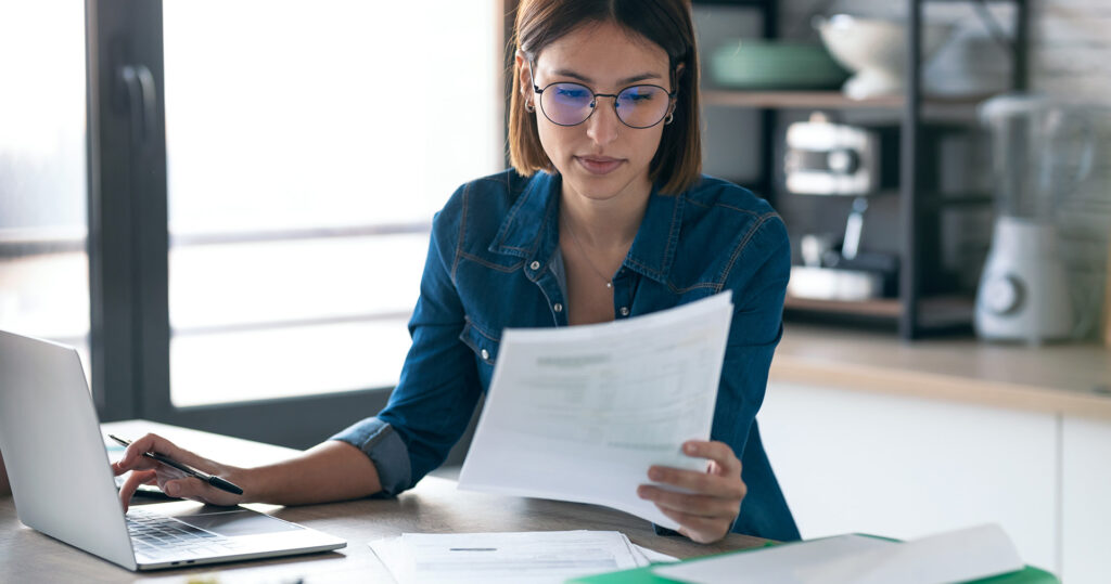 Woman at laptop holding papers