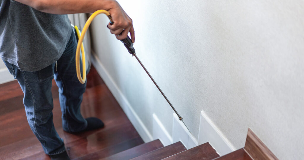 Pest control tech spraying stairs in home