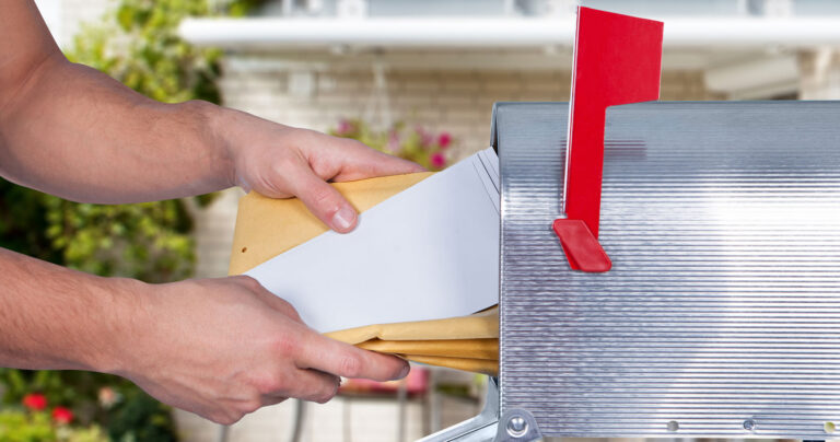 a man putting mail into a mailbox